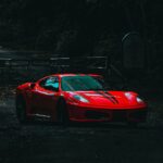 Dramatic shot of a red sports car on a secluded, dark forest road.