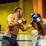 Two boxers in a high-energy match inside an arena showcasing intense combat and skill.