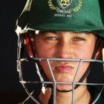 Focused young cricketer wearing a green helmet, preparing for the game.