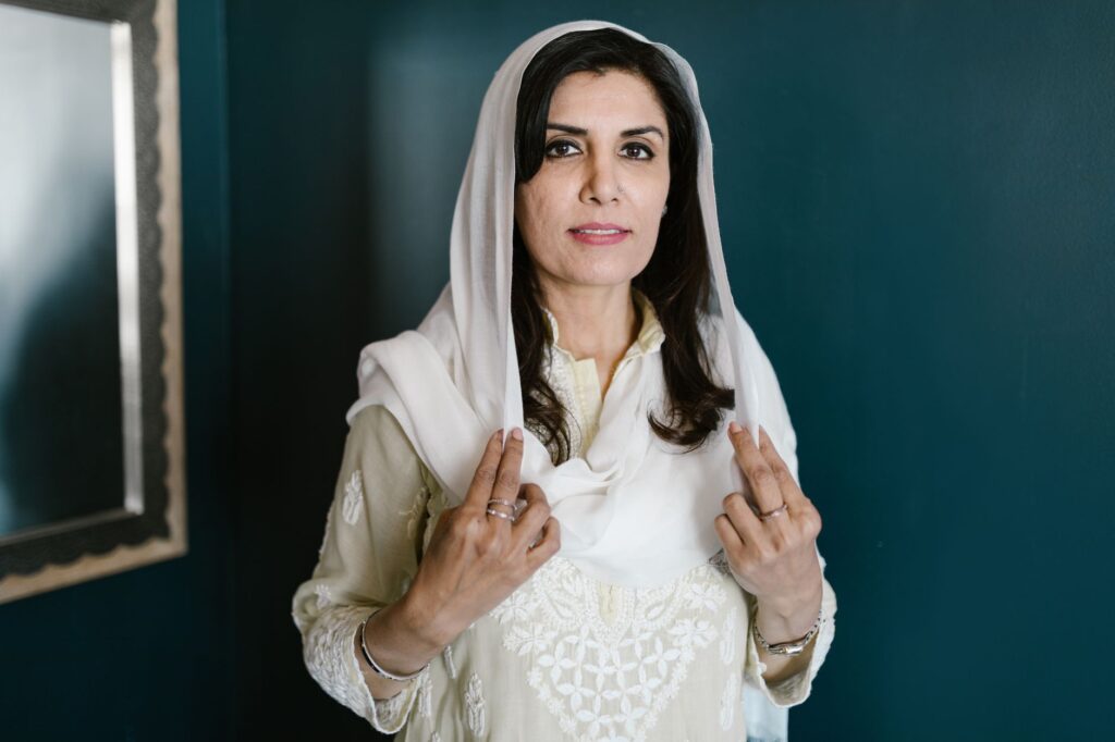 Portrait of an elegant woman in traditional attire with a headscarf, captured indoors.