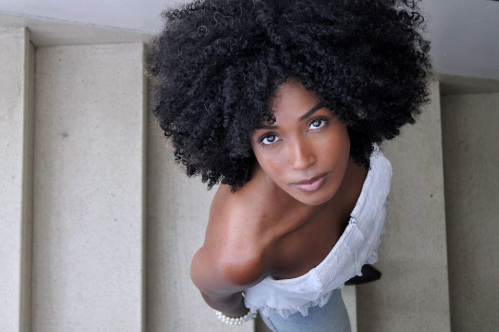 Elegant portrait of a woman with afro hairstyle looking up from staircase.