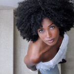 Elegant portrait of a woman with afro hairstyle looking up from staircase.