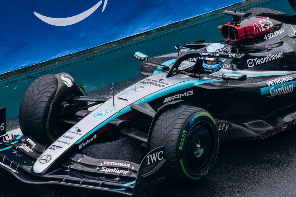 Close-up of a sleek race car navigating a wet track, showcasing its speed and design.