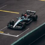 Dynamic shot of a Formula One car racing on wet asphalt, showcasing speed and precision.