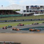 Thrilling car race at Silverstone Circuit with packed grandstands and vibrant crowd.