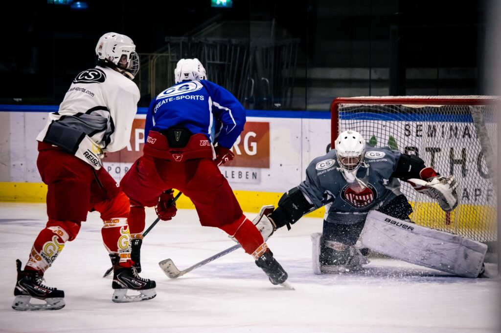 Dramatic moment in an indoor ice hockey game with players in action against a goalie.