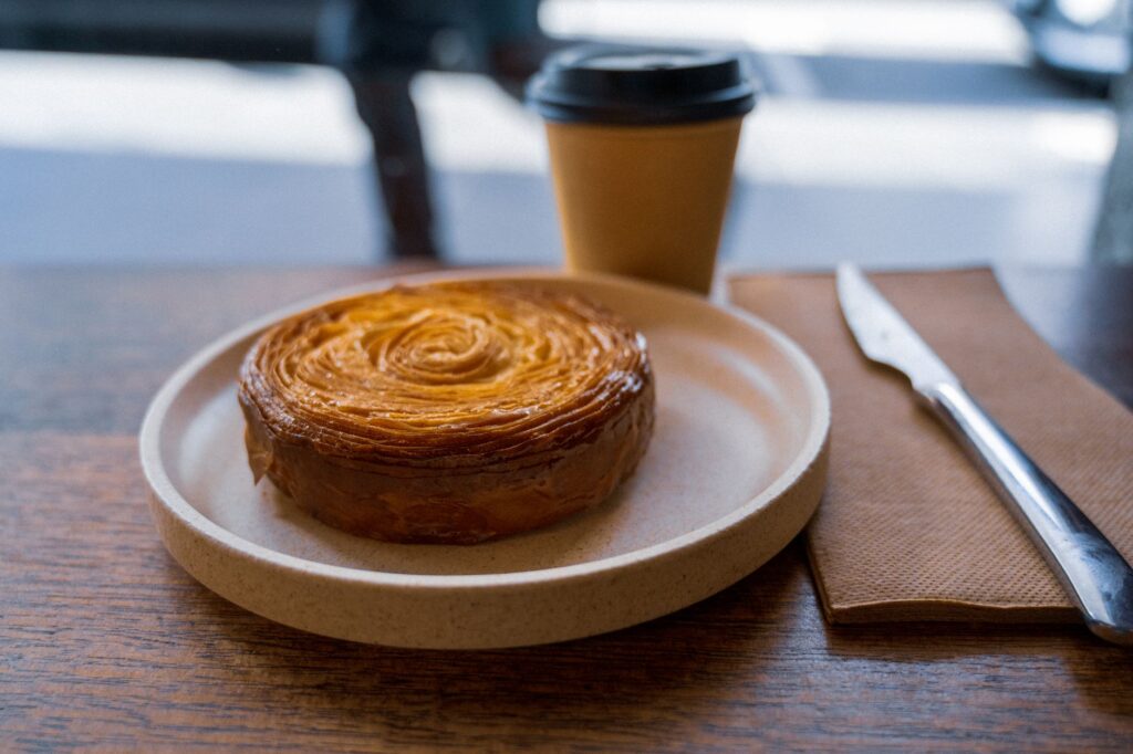 A beautifully baked pastry with a coffee cup in a Melbourne café setting, evoking a cozy atmosphere.