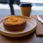 A beautifully baked pastry with a coffee cup in a Melbourne café setting, evoking a cozy atmosphere.