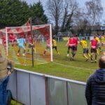 Action-packed amateur football match in progress, England. Enthusiastic crowd cheering.