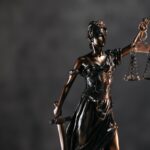 Detailed bronze Lady Justice statue with scales and sword against a dark background, symbolizing law and justice.