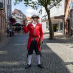 A historical reenactor in period costume poses in a charming Tondern street, Denmark.