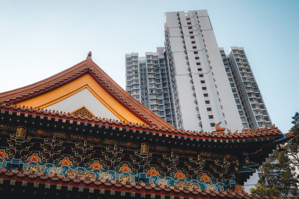 Ancient temple architecture contrasted with modern skyscraper in Hong Kong.