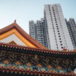 Ancient temple architecture contrasted with modern skyscraper in Hong Kong.