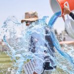A joyous scene of a coach being doused with water during an outdoor sports celebration.