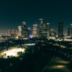 A stunning aerial view of Houston's illuminated skyline at night, showcasing skyscrapers and urban parks.