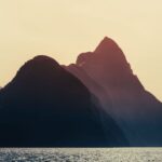 Dramatic sunset over Milford Sound, New Zealand, highlighting the majestic mountains and serene sea.