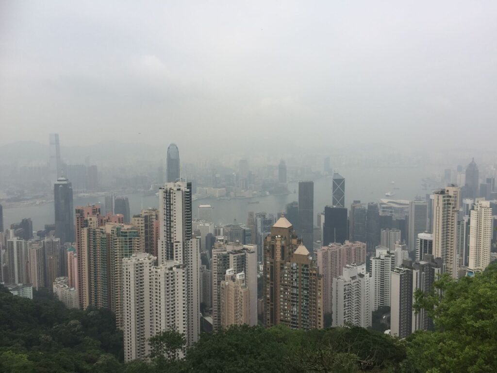 Foggy skyline of Hong Kong Island as seen from Victoria Peak, showcasing skyscrapers and urban landscape.