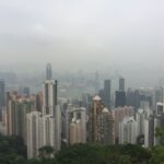 Foggy skyline of Hong Kong Island as seen from Victoria Peak, showcasing skyscrapers and urban landscape.