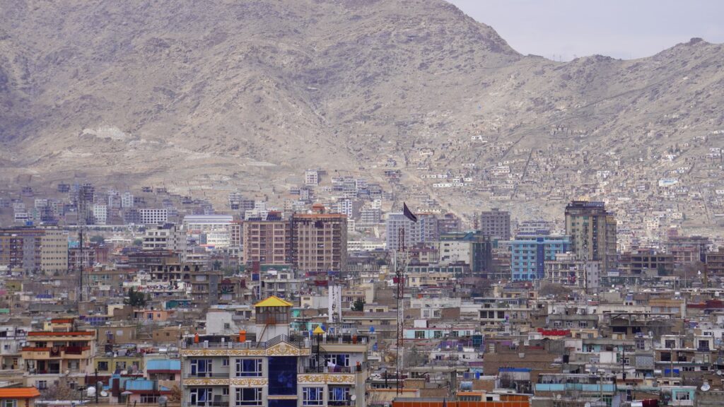 A panoramic view of Kabul city with high-rise buildings set against a mountainous backdrop.