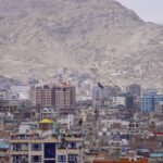 A panoramic view of Kabul city with high-rise buildings set against a mountainous backdrop.