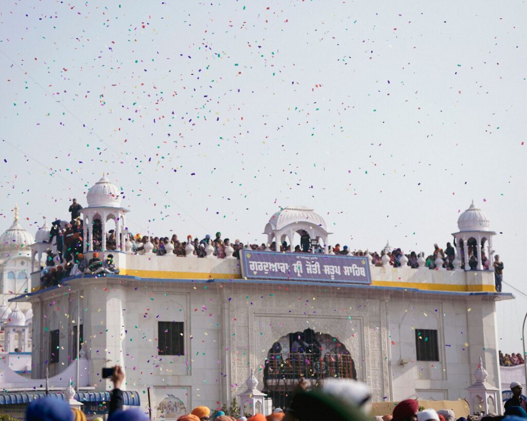 Crowds gather at a classic dome for a traditional festival with colorful confetti in the air.