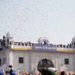Crowds gather at a classic dome for a traditional festival with colorful confetti in the air.