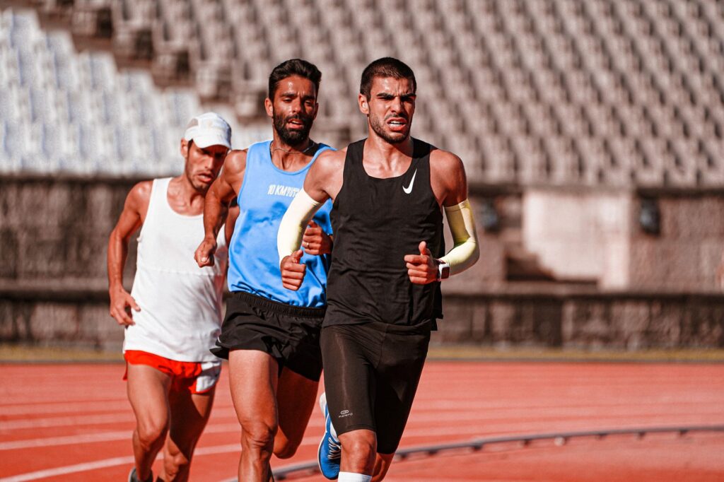 Three determined athletes compete in a track and field race, showcasing energy and focus.