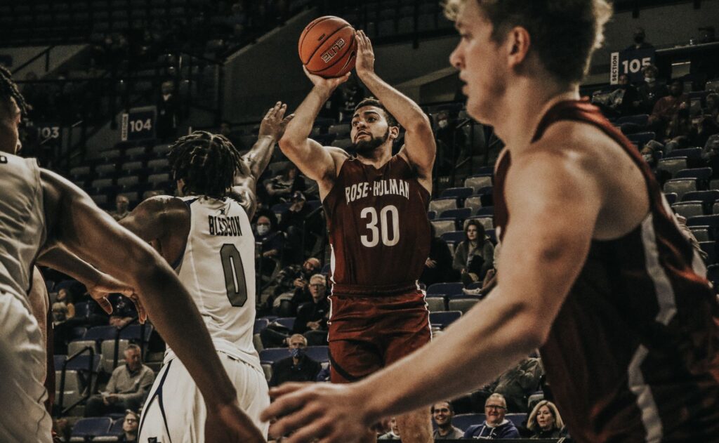 Basketball players in an intense college game action, showcasing skill on court.