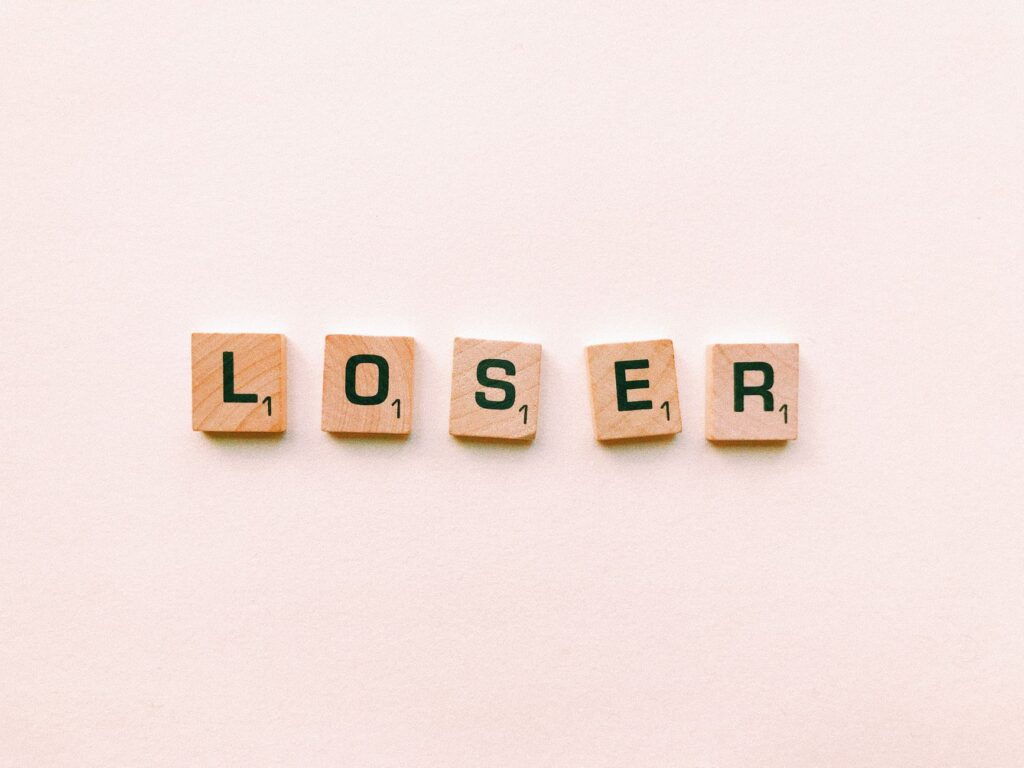 Five wooden tiles spell the word 'loser' in a minimalist and symbolic photo.