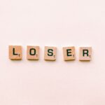Five wooden tiles spell the word 'loser' in a minimalist and symbolic photo.