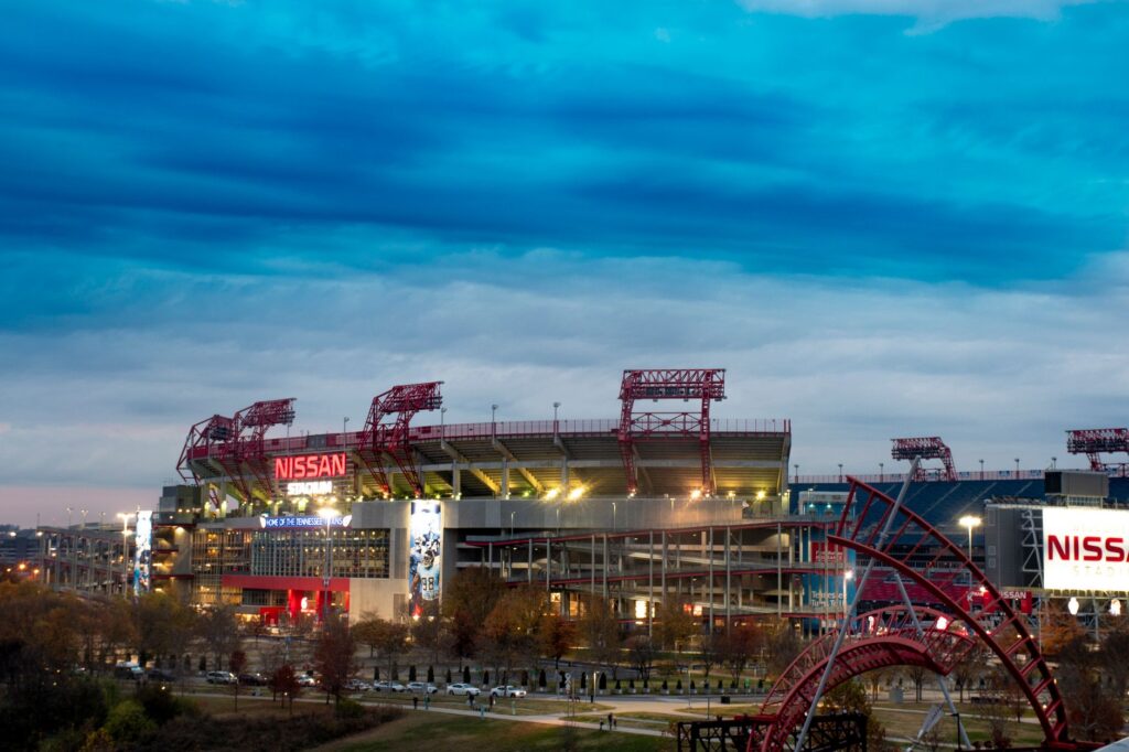 View of Nissan Stadium in Nashville, Tennessee, under a dramatic cloudy sky at dusk.