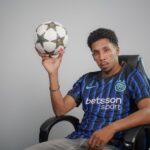 Casual portrait of a football player holding a ball indoors. Stylish and confident.
