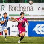 Two soccer players compete intensely for the ball during a vibrant outdoor match.