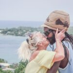 A multiracial couple shares a romantic kiss overlooking the ocean in Jamaica.