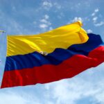 Vibrant Colombian flag waving against a bright blue sky with additional colorful maritime flags.