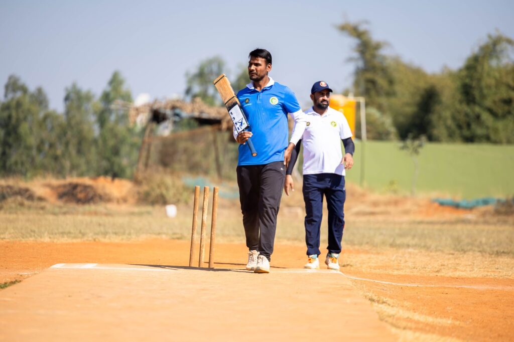 Two men playing cricket outdoors in a sunny field.