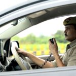 A police officer communicates via CB radio while driving a patrol vehicle, focused and on duty.