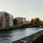 Picturesque view of the river in Galway, Ireland at sunset with historic buildings and a charming bridge.