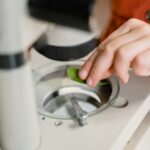 A close-up shot showing a hand placing a leaf under a microscope for scientific study.