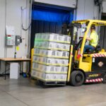 A warehouse employee operating a forklift to move stocked goods indoors. Perfect for industry and logistics visuals.