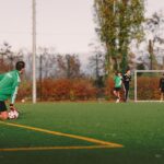 Men playing a casual soccer match on an outdoor field in Berlin during autumn.