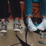 Two pairs of sneakers hanging over a graffiti wall, showcasing urban street style.