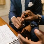 Two businessmen in suits finalize a contract, highlighting teamwork and agreement.