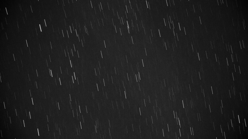Black and white photo of star trails created with long exposure at night.