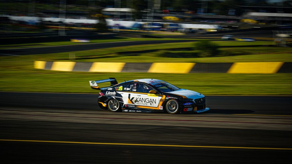 Race car speeding on track during a daytime event showcasing motorsport action.