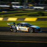 Race car speeding on track during a daytime event showcasing motorsport action.