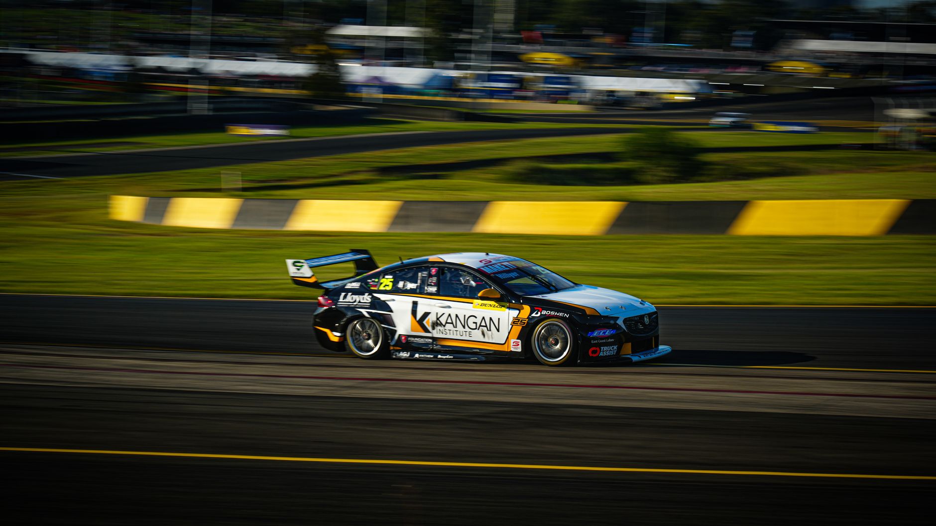 Race car speeding on track during a daytime event showcasing motorsport action.