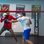 Two men engaged in an intense mixed martial arts training in an indoor gym.