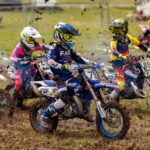 Exciting youth motocross race on a muddy track showcasing young riders in action-packed competition.