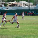 Intense soccer game in Mina, Mendoza, Argentina showcasing teamwork and action on a sunny day.